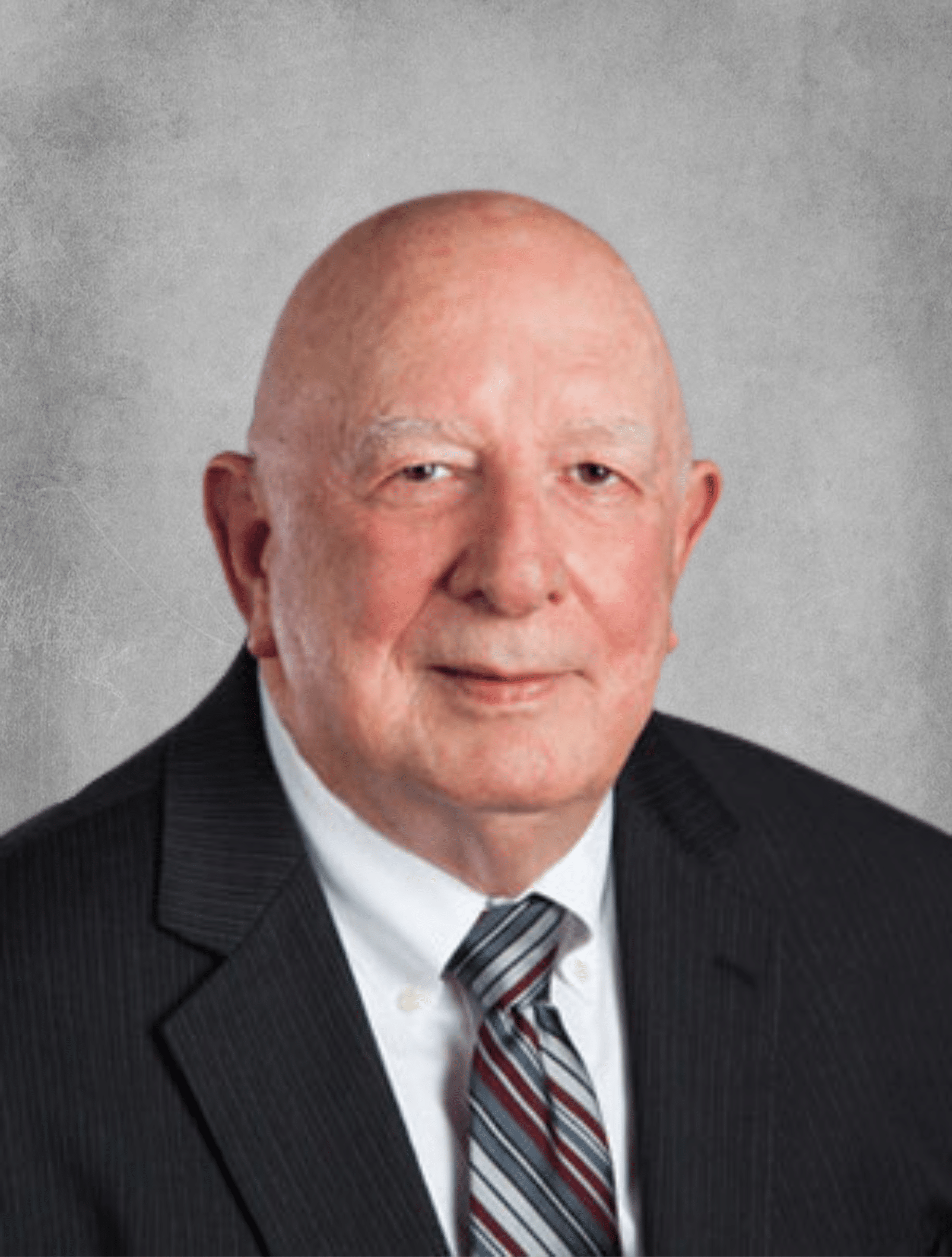 Older white gentleman standing in front of backdrop.